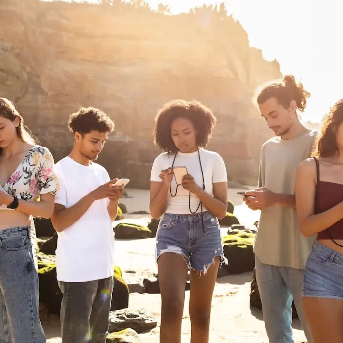 Busy serious young diverse people typing on smartphones on beach. News, modern app for social networks, friendship together in summertime, walk, vacation holiday and travel, gadget addiction